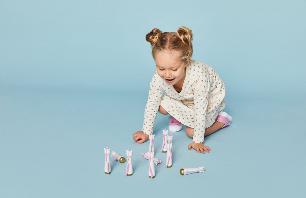 Kid playing with Sunnylife unicorn skittles on the floor