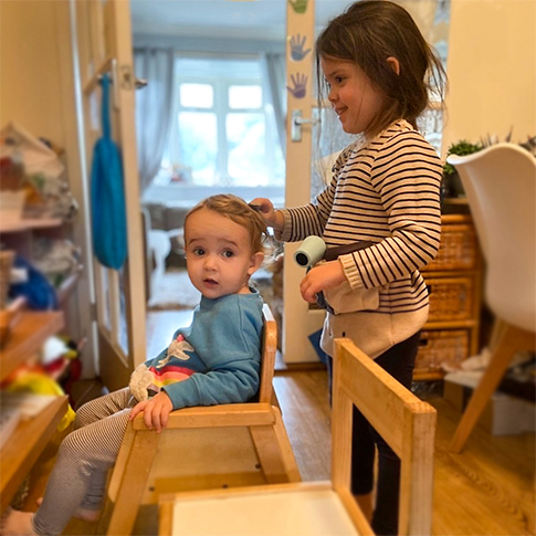 Little girl pretending to dry another child's hair