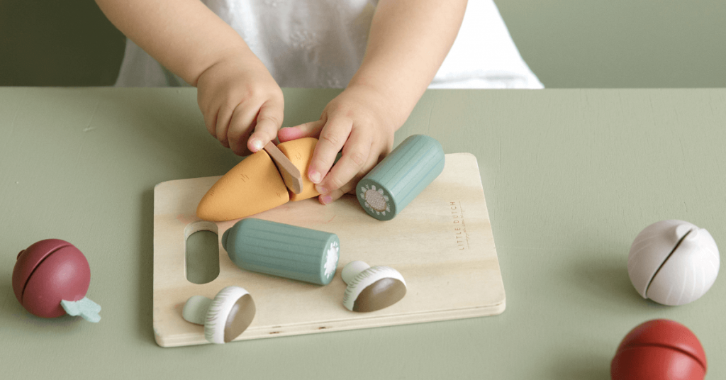 Are wooden toys better? Child cutting wooden vegetable toy